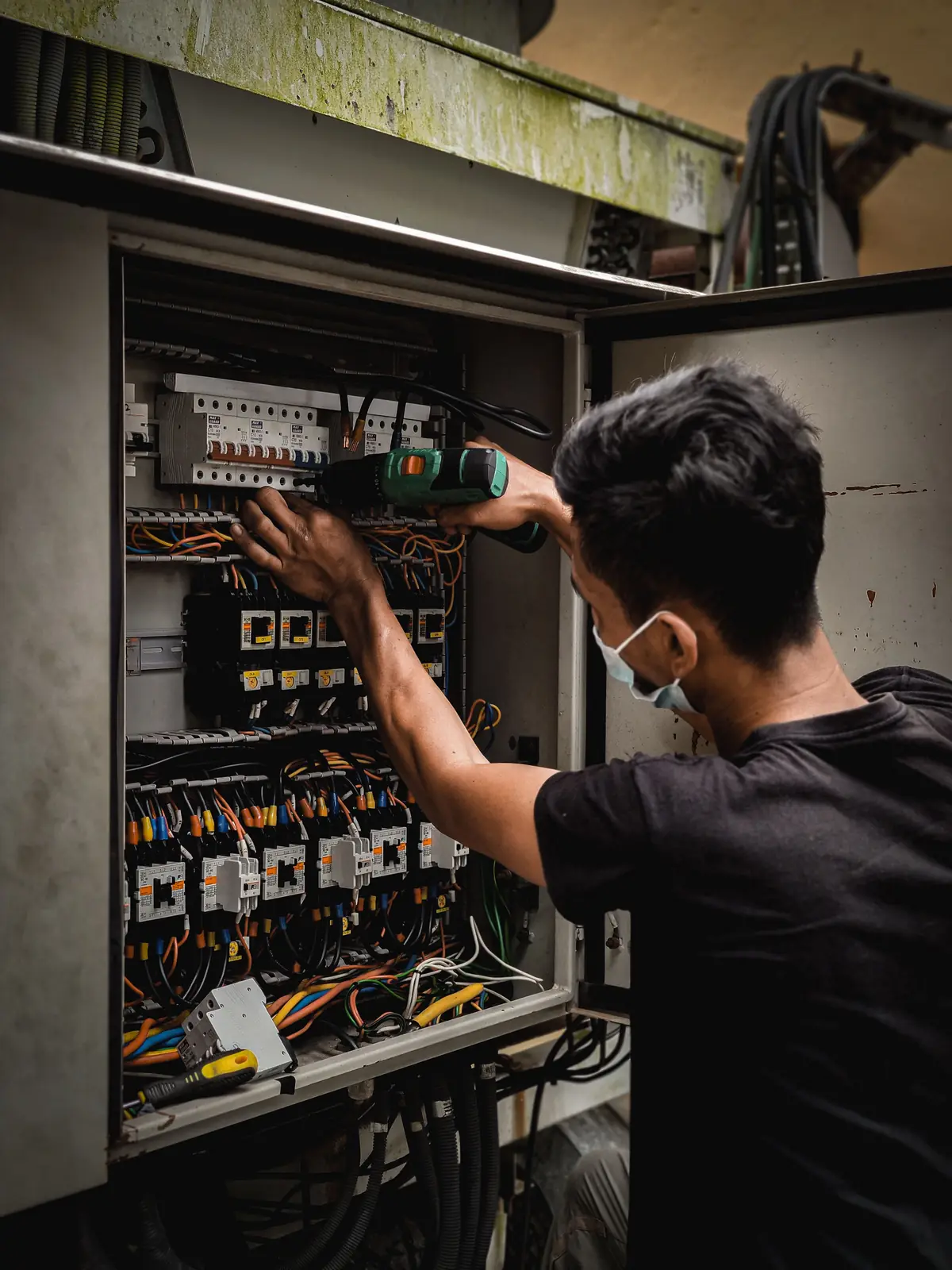 An electrician working inside a large distribution board, for commercial electrical in Windsor